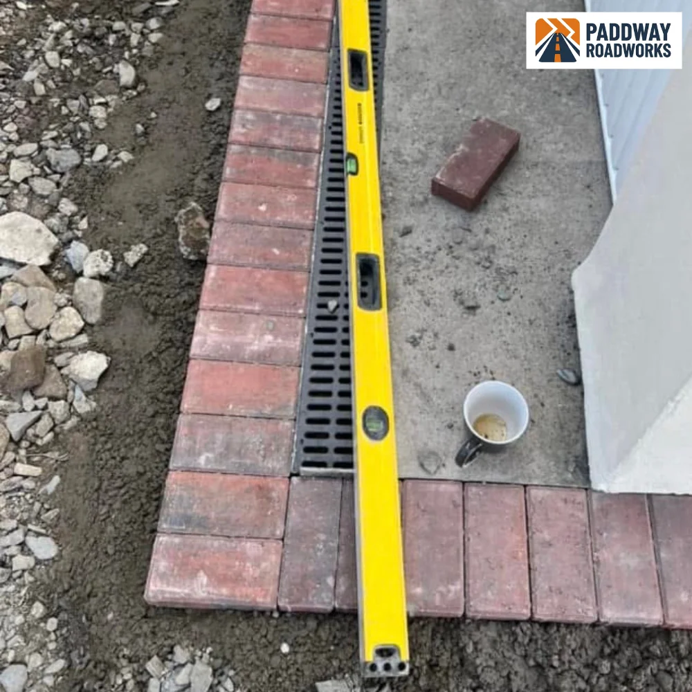 Block paving being laid to a crisp edge against a new kerb, checked with a spirit level