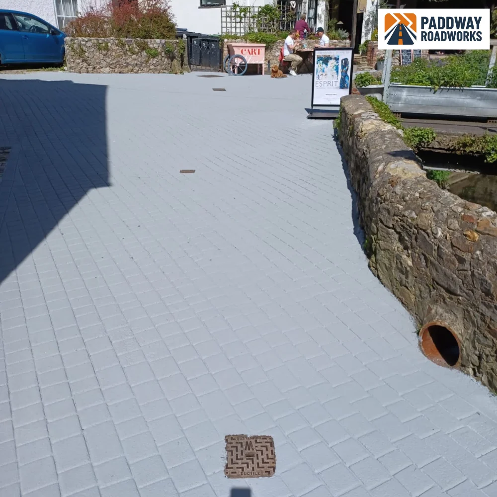 Block paved courtyard finished against a stone wall with a granite kerb