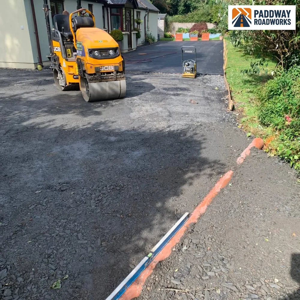 Ride-on road roller compacting a fresh bay of hot tarmac